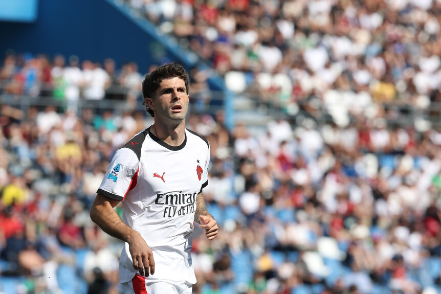 Cristian Pulisic standing in a soccer stadium in frot of spectators.