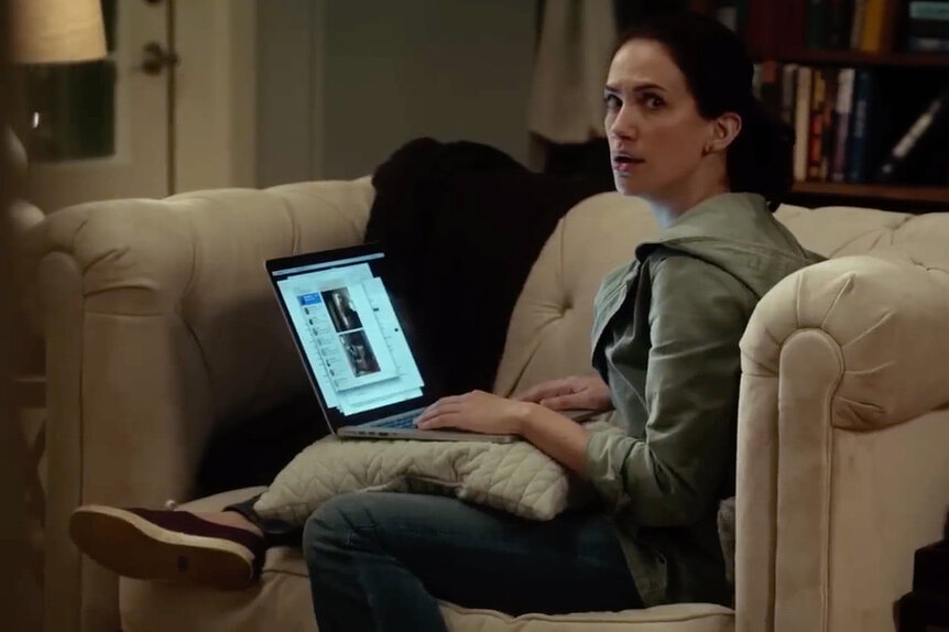 A woman sitting in a lounge chair while on a laptop computer.