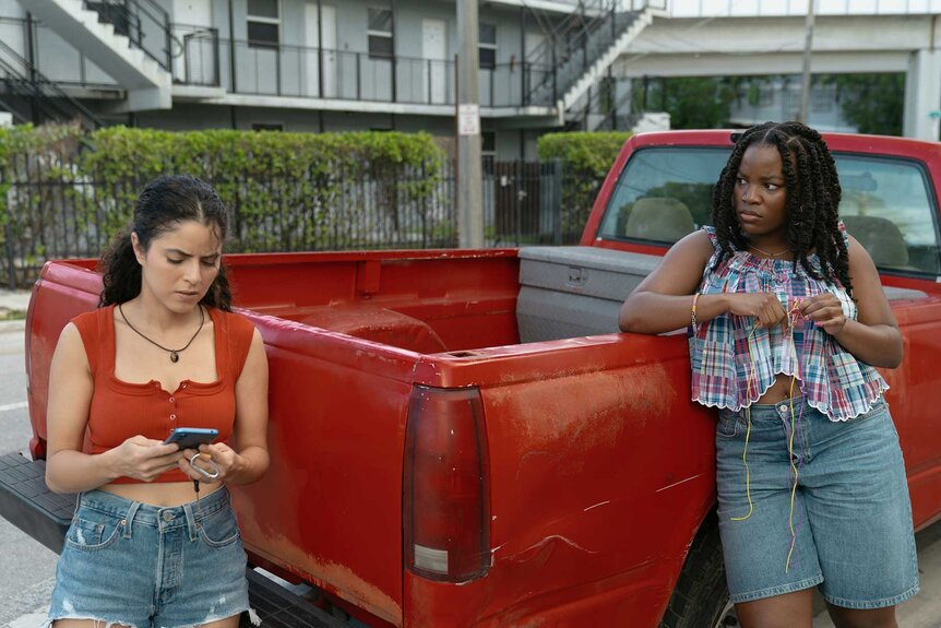Etta and Lovely leaning against a red truck in M.I.A. Season 1.