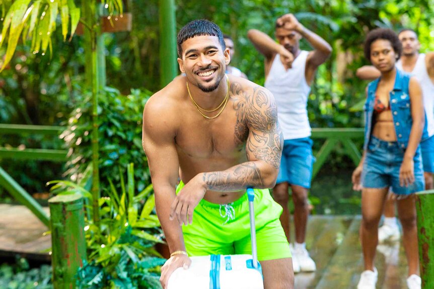 Sean David Feifel kneeling with a suitcase on Love Island USA Season 8.