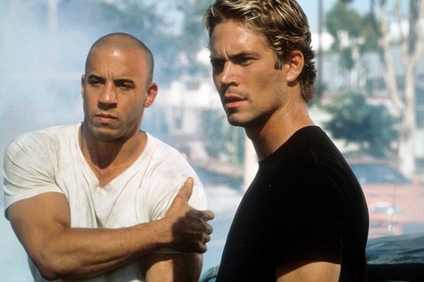 Dominic Toretto and Brian O'Conner standing together while looking off to the side in The Fast And The Furious (2001).