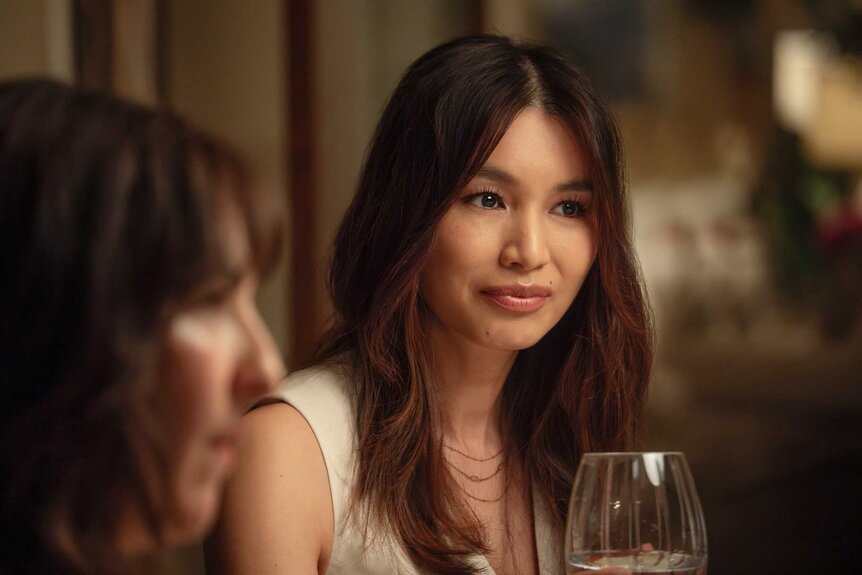 Gigi sitting at a table with wine in The Five Star Weekend Season 1.