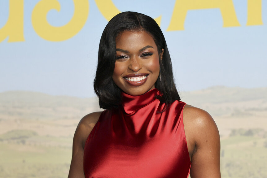 Aziza Scott smiling in front of a step and repeat.