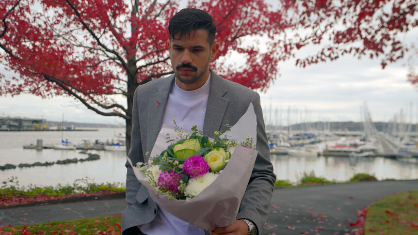 Felipe Cruz holding a bouquet of flowers at a park.