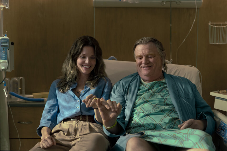 Meghann Fahy as Charlie and Brendan Gleeson laying in a hospital bed on The Good Daughter Season 1.